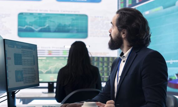 Corporate employee looking into project details and timetables Corporate employee looking into project details and timetables in open coworking space, establishing budget and operations to accomplish goals in a competitive business environment.